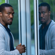 Yahya Abdul-Mateen II, in a gray hoodie, stands opposite his reflection in a glass door in Watchmen.
